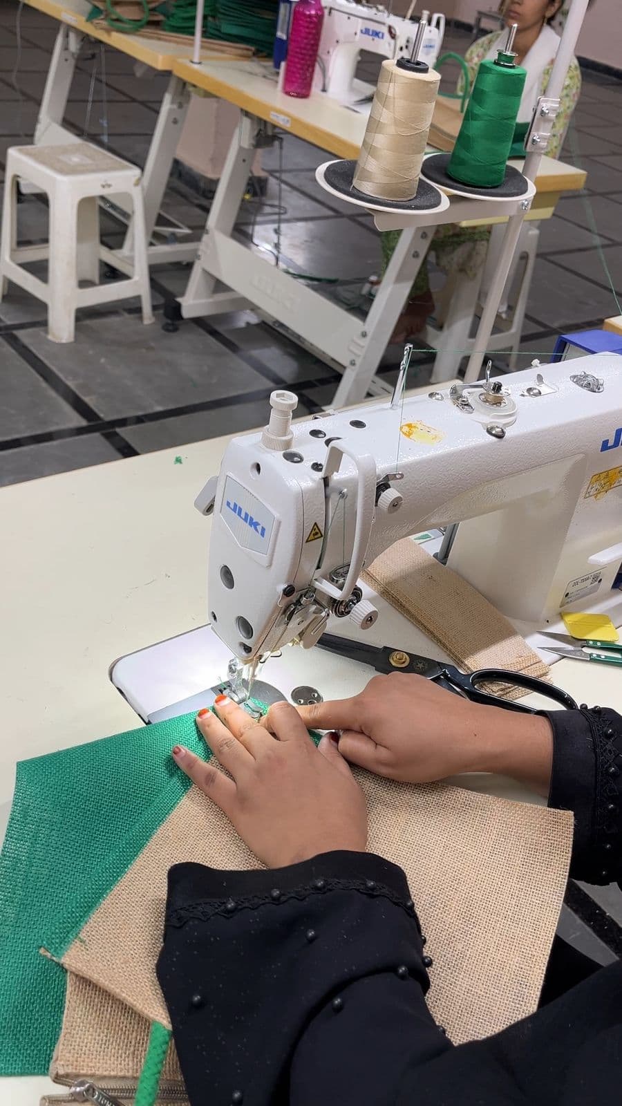 HuskWorks artisan hand-guiding jute fabric through a stitching machine at the Hyderabad workshop